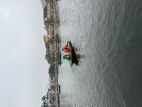 People paddling in small boats on a calm river under hazy conditions.