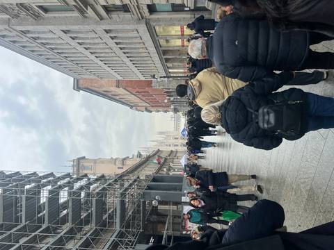 Busy street in Milan with the Duomo visible in the distance.