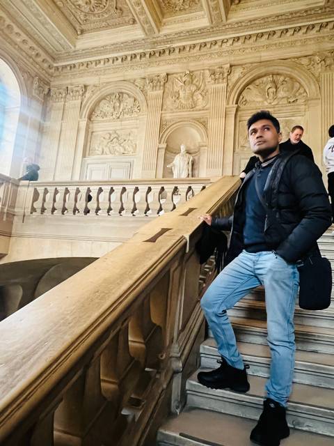 Individual inside a historic building by stairs.