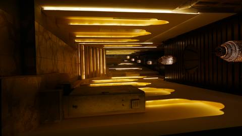 Narrow corridor with glowing yellow alcove lights and hanging chandeliers leading up marble steps.