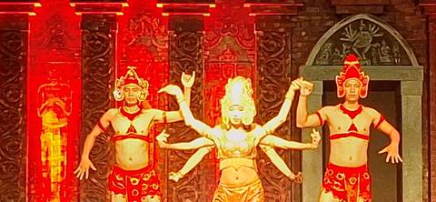 Stage performance with dancers in traditional bright red and gold outfits.
