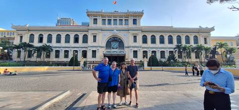 Group of tourists posing in front of a historic building with a yellow facade.