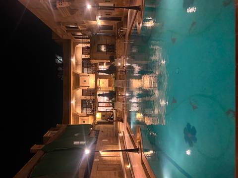 Night view of a hotel with a swimming pool in the foreground.
