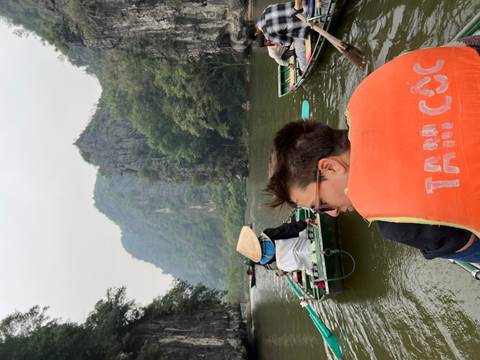 Tourist in a boat on a river with limestone karsts in the background.