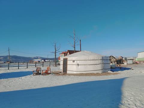 Traditional yurt with snowy ground under a clear sky.