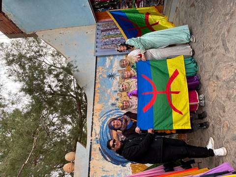 People dressed in traditional attire holding a colorful flag.
