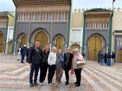 Group of tourists posing in front of ornate gates.