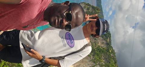 Two people taking a selfie with a cliff and ocean in the background.