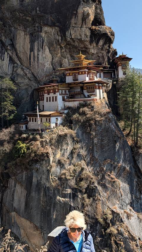 Tiger's Nest Monastery dramatically clings to the side of a sheer cliff amid forested mountains.