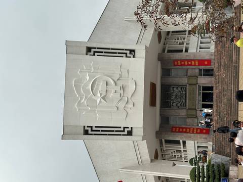 Facade of the Ho Chi Minh Museum with socialist relief, red banners and visitors on the steps under grey sky.