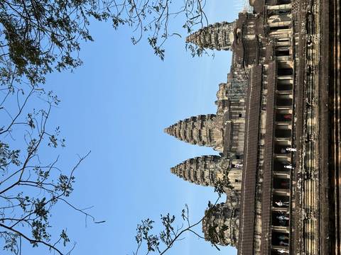 Iconic triple towers of Angkor Wat rising above the main gallery with tourists exploring below.
