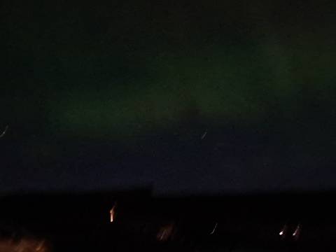Dark night sky with faint green aurora barely visible above a shadowed horizon.