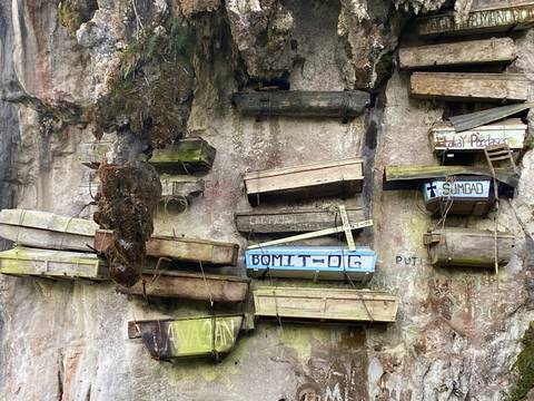 Ancient hanging coffins affixed to a limestone cliff face with weathered wood