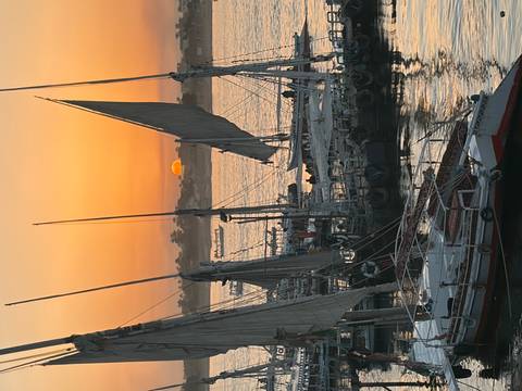 Traditional feluccas moored on the Nile as the sun sets in a vivid orange sky over Aswan