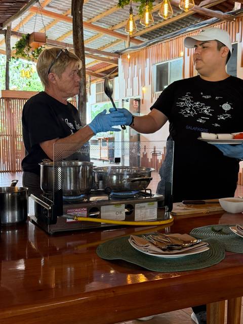 Cooking demonstration with two participants preparing food on portable gas burners indoors.