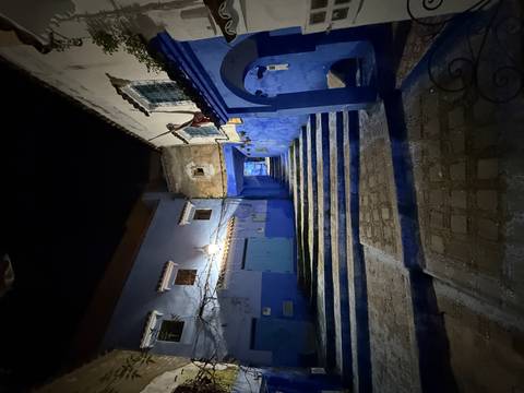 Empty blue alleyway with stairs and lantern in the medina at night.