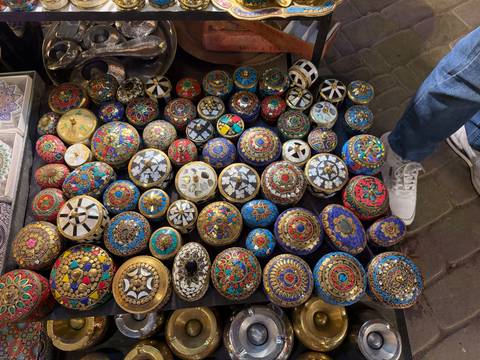Close-up display of ornate hand-painted trinket boxes in vibrant colours at a night market.