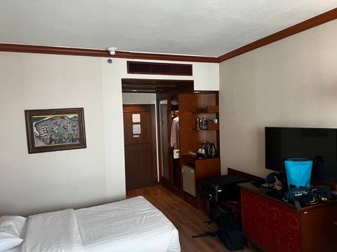 Modest hotel room interior with luggage and personal items scattered near a TV and minibar.