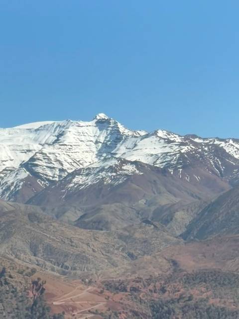 Snow-capped peaks of the High Atlas Mountains under a clear blue sky.