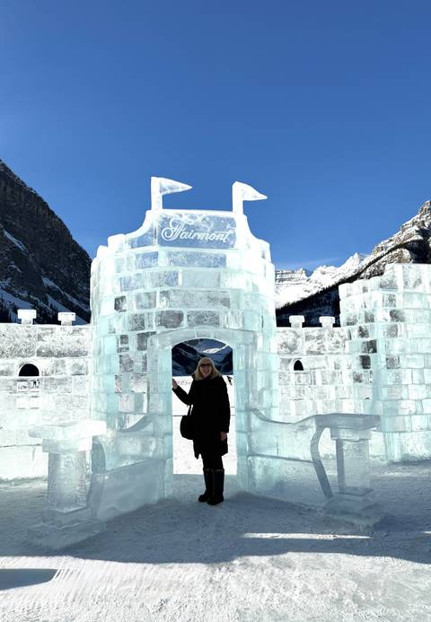 A woman stands at the entrance of a translucent ice castle bearing the Fairmont name.