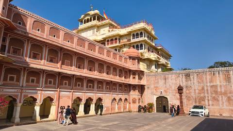 Courtyard of the Jaipur City Palace complex with visitors strolling under clear blue sky.