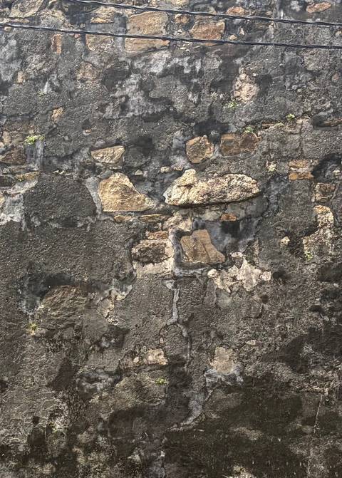 Detail of an old weathered stone wall showing rough textures and patches of different colored stones.