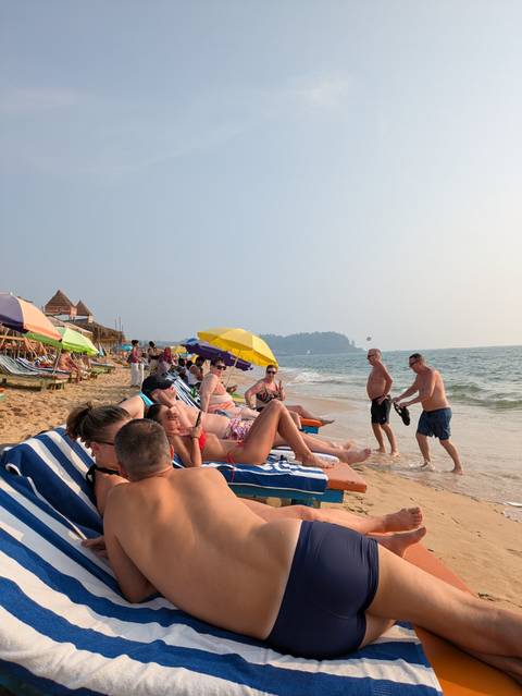 Leisurely beach scene with sunloungers and colourful umbrellas on a sandy Goa shoreline.