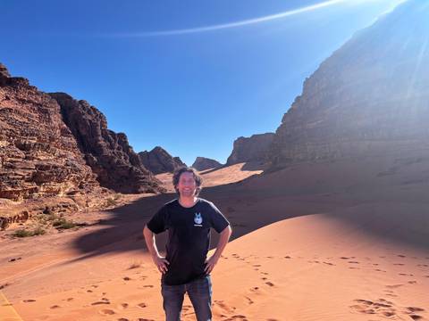 Traveler stands confidently between towering sandstone walls in Wadi Rum’s sweeping desert valley.