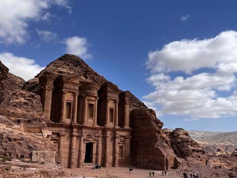 The Monastery at Petra rises majestically from rose-colored cliffs under a partly cloudy sky.