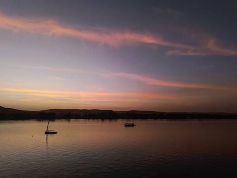 Pastel twilight sky reflected on calm Nile waters with small sailboats anchored.
