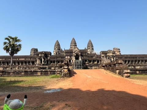 Front view of majestic Angkor Wat temple complex under cloudless blue sky, with scaffolding on central causeway.