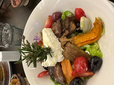 Colorful salad with roasted vegetables, olives and goat cheese garnished with rosemary