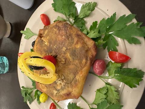 Plated Moroccan pastry garnished with olives, tomatoes, herbs and a lemon ring