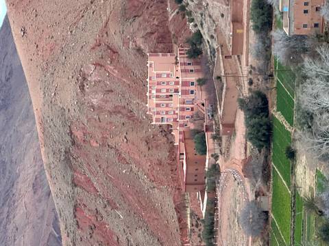 Isolated kasbah-style hotel set against rugged red mountains and terraced fields