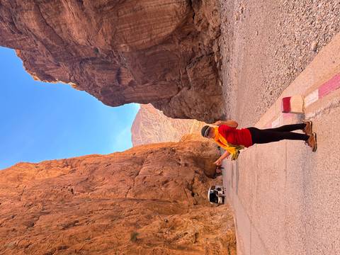Traveler standing triumphantly in the narrow orange cliffs of Todra Gorge