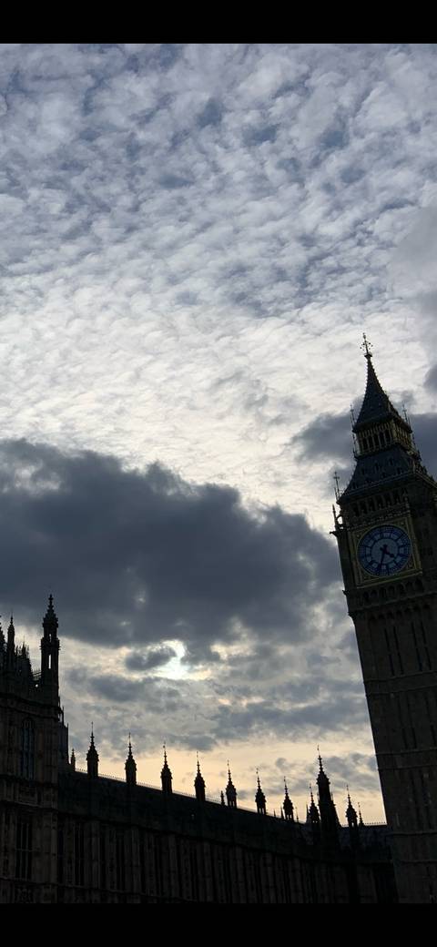 Dramatic cloudy sky with the clock face of Big Ben peeking on the right