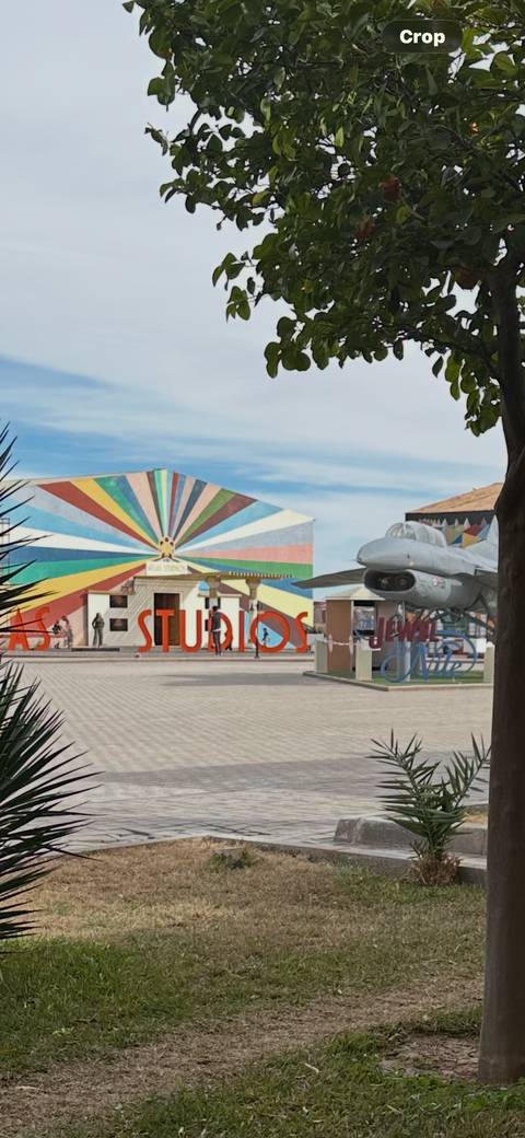 Colorful Atlas Studios facade with a fighter jet display and visitors strolling