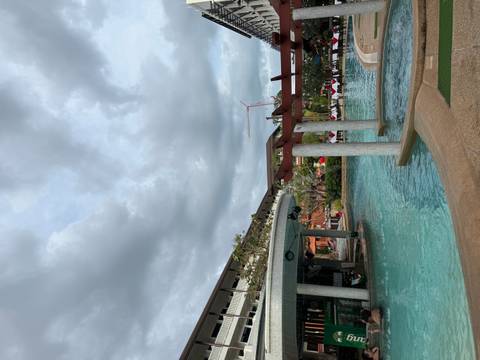 Resort swimming pool surrounded by buildings under a cloudy sky.
