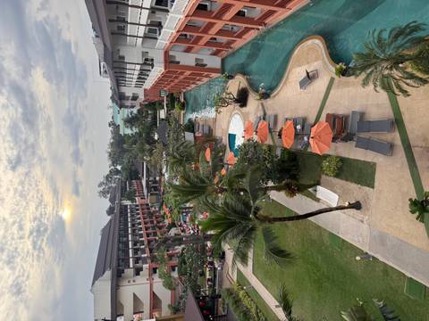 Elevated sunset view of a large resort with pools, palm trees and loungers.
