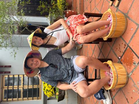 Couple soaking their feet in flower-filled wooden tubs during a spa treatment.