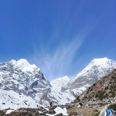 Panoramic view of twin snow peaks against a deep blue Himalayan sky.