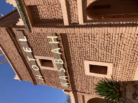 Close view of adobe brick wall with large letters spelling 'HOTEL KASBAH'.