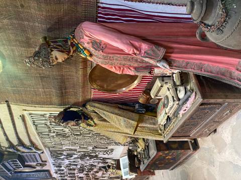 Display of traditional Berber clothing and antique weapons inside a small desert museum.