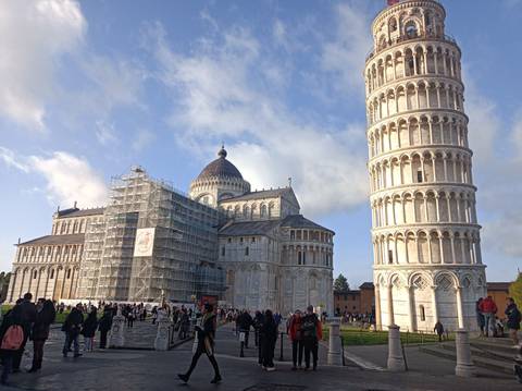 The Leaning Tower of Pisa and Pisa Cathedral rise above a busy square filled with visitors.