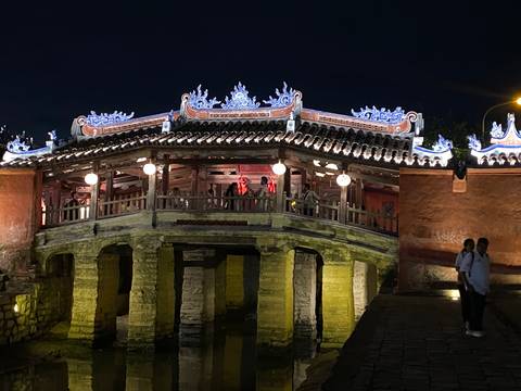 Japanese Covered Bridge in Hoi An illuminated at night with visitors on the span.