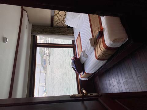 Cozy cruise cabin with neatly made bed and panoramic window overlooking harbor.