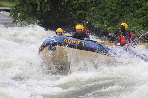 White-water rafting team in a blue raft crashing through rapids wearing yellow helmets.