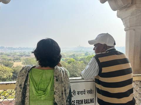 Man and woman lean on balcony railing admiring hazy distant view of river plain