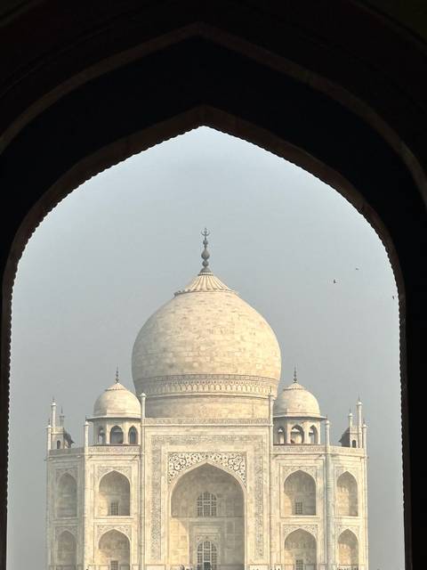 Close frame of Taj Mahal dome seen through dark arched window