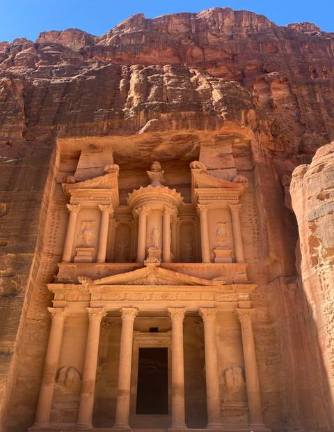 Detailed façade of the Treasury at Petra carved into rose-red sandstone cliffs basking in natural light.